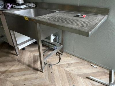 a stainless steel sink and a metal table in a kitchen