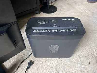 a black electronic device sitting on the floor next to a computer monitor