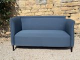 a blue couch sitting in front of a stone wall