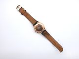 the watch has a brown leather strap with a gold buckle