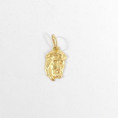 un gros plan d'un pendentif représentant une tête de Jésus en or sur fond blanc