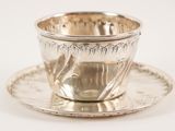 a silver cup and saucer sitting on a saucer