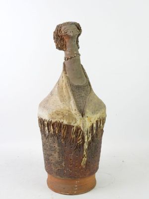 a small vase with a statue of a woman on it