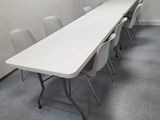 une longue table avec des chaises dans une pièce aux murs blancs