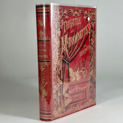 an old book with a red cover sitting on top of a white table