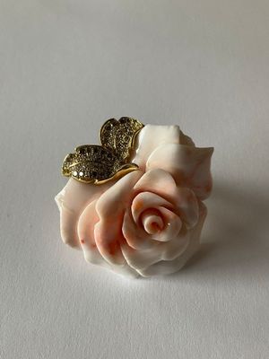 a white rose with a gold butterfly on top of it