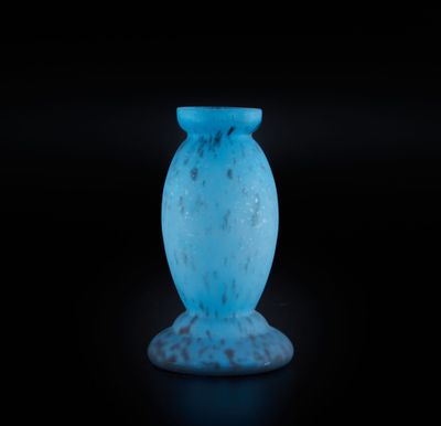 un vase en verre bleu posé sur une surface noire