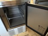 a small freezer that is open on a tile floor