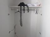 a white closet with a shelf and clothes hanging on it