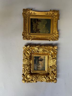 Deux tableaux dans des cadres dorés sont accrochés à un mur blanc dans une pièce