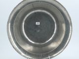 a silver plate on a metal stand on a white surface