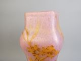 un vase rose orné de fleurs dorées, posé sur une table