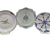 three plates with blue and white designs on them on a stand