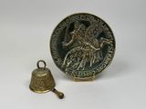 une vieille cloche et une médaille sur un fond blanc