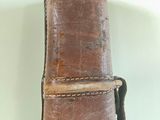a brown leather guitar case with a strap on it