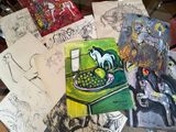 many drawings on a table with a cat on top of it