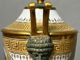 a white and gold vase with a gold handle on a tray