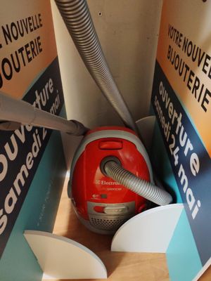 un aspirateur rouge qui se trouve dans une boîte posée par terre