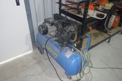 un compresseur bleu posé dans un garage, à côté d'une étagère