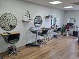 a photo of a salon with chairs and mirrors on the wall