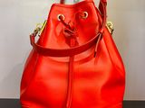 un sac seau rouge posé sur une table noire près d'un mur blanc