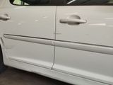 a white car that has been dented and is parked in a garage