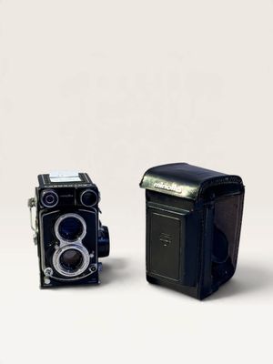 two old cameras sitting next to each other on a white surface