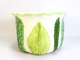 a green and white planter with leaves on it