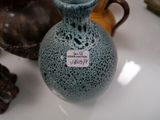a blue vase with a tag on it sitting next to other vases