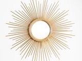 un miroir doré à rayons, posé sur une table en bois