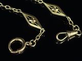 two pieces of gold chain with a clasp on a black background