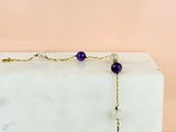 un gros plan d'un collier violet et blanc posé sur un bloc de marbre