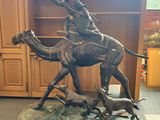 statue of a man riding a camel with a dog on a cart