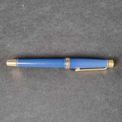 a close up of a blue fountain pen on a gray surface