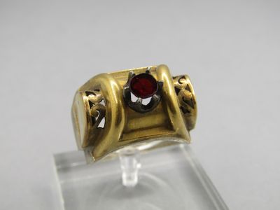 a close up of a gold ring with a red stone