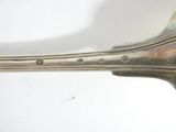 a silver spoon with a handle on a white surface
