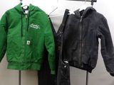 deux vestes et un pantalon suspendus à un portant dans une pièce