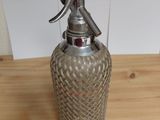 a glass bottle with a metal handle on a wooden table