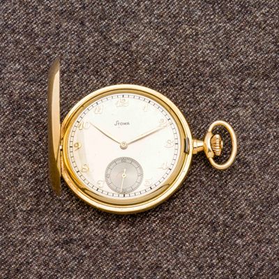 une montre de poche en or posée sur une surface marron