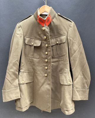 une vieille veste militaire suspendue à un cintre accroché au mur