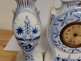 two blue and white vases with a clock on top of them