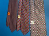 three ties hanging on a blue wall with a tag on it