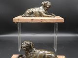 a bronze statue of two dogs laying on top of a wooden platform