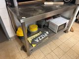 une table en métal sur laquelle est posée une pizza, dans une cuisine
