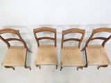four wooden chairs are lined up against a white wall