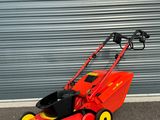 une tondeuse à gazon rouge garée devant la porte d'un garage