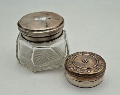 a small glass jar with a silver lid next to a small glass jar with a silver lid