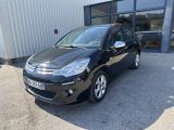 une voiture noire garée devant un immeuble, à côté d'un parking