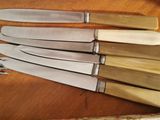 several knives are lined up on a table with a knife in the middle