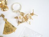 some gold jewelry on a white table with a gold fan